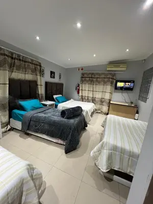 a bedroom with two beds and a flat screen tv at claremont AN guesthouse in Cape Town