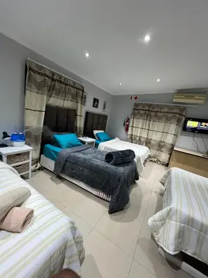 a bedroom with three beds and a flat screen tv at claremont AN guesthouse in Cape Town