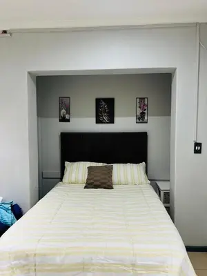 a large white bed in a bedroom with pictures on the wall at claremont AN guesthouse in Cape Town