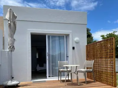 a white house with chairs and a table on a deck at Mountain View Studio Hermanus in Hermanus