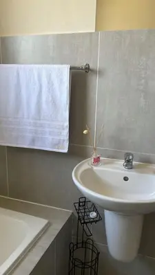 a bathroom with a white sink and a bath tub at Delightful Retreat in Parklands,Cape Farms,Cape Town in Cape Town