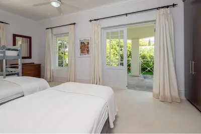 a white bedroom with two beds and a sliding glass door at Fir Close 3 bedroom in Hermanus