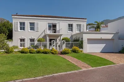 a white house with a gate and a garage at Fir Close 3 bedroom in Hermanus