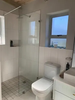 a bathroom with a toilet and a glass shower at Taylah's Hideaway in Bettyʼs Bay