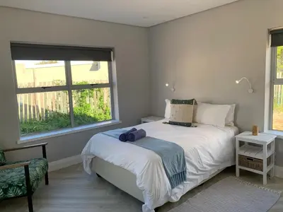 a bedroom with a white bed and a window at Taylah's Hideaway in Bettyʼs Bay