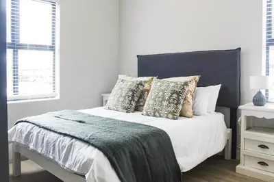 a white bedroom with a large bed with pillows at Flat in Security Estate - Zomerwind Apartments in Oakdale