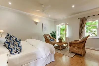 a bedroom with a bed and two chairs and a window at Auberge Burgundy Boutique Hotel & Spa in Hermanus
