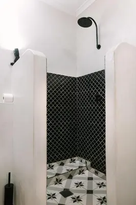 a bathroom with a shower with a black and white tile floor at Auberge Burgundy Boutique Hotel & Spa in Hermanus