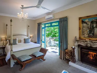 a bedroom with a bed and a fireplace at Franschhoek Country House & Villas in Franschhoek