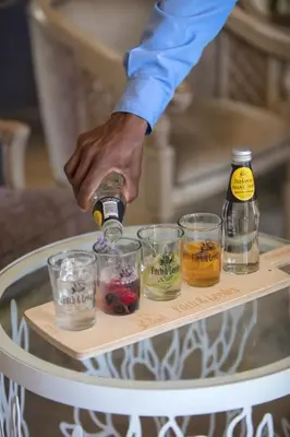 a person pouring a drink into glasses on a table at Franschhoek Country House & Villas in Franschhoek