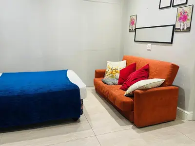 an orange couch with pillows on it in a room at Annika`s dormitory in claremont in Cape Town