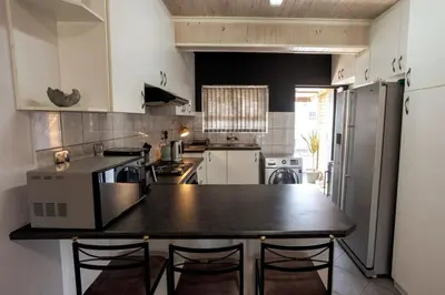 a kitchen with a black counter top and a refrigerator at The Palm in Kraaifontein