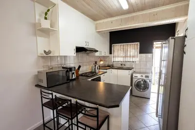 a kitchen with a black counter top and white appliances at The Palm in Kraaifontein
