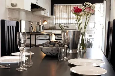 a kitchen with a table with glasses and a vase of flowers at The Palm in Kraaifontein