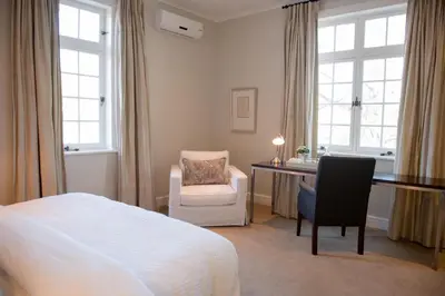 a bedroom with a bed and a desk and a chair at River Manor Boutique Hotel by The Living Journey Collection in Stellenbosch