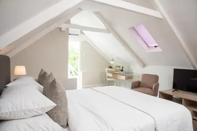 a white bedroom with a bed and a tv at River Manor Boutique Hotel by The Living Journey Collection in Stellenbosch