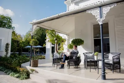 a man sitting on a porch with a baby at River Manor Boutique Hotel by The Living Journey Collection in Stellenbosch