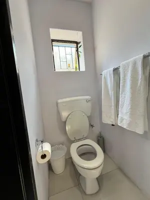 a bathroom with a toilet and a window and towels at Pelikaan 5 in Stellenbosch