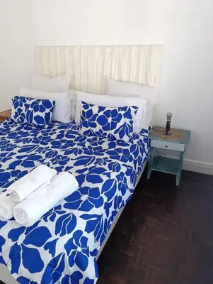 a bed with blue and white sheets and pillows at Ascot manor in Cape Town