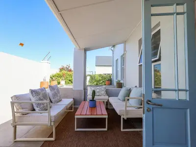 a porch with a couch and chairs and a table at Salt & Butter in Hermanus
