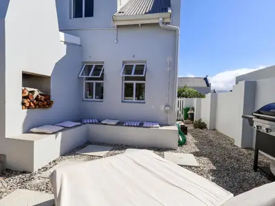 a white house with two benches on the side of it at Salt & Butter in Hermanus