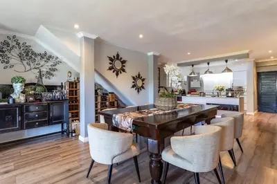 a kitchen and dining room with a wooden table and chairs at Luxury Lakeside Lodge at Jack Nicklaus Golf Estate in Simondium