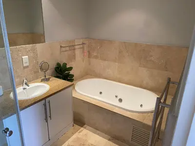 a bathroom with a tub and a sink at Luxury Lakeside Lodge at Jack Nicklaus Golf Estate in Simondium