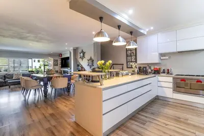 a kitchen with white cabinets and a dining room at Luxury Lakeside Lodge at Jack Nicklaus Golf Estate in Simondium