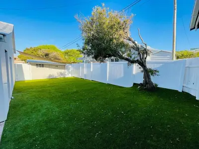 a yard with a white fence and a tree at Sea view holiday home in Kleinmond