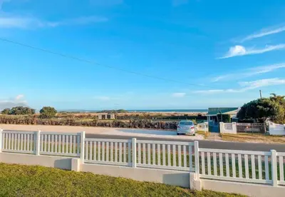 a white fence with a car parked in a parking lot at Sea view holiday home in Kleinmond