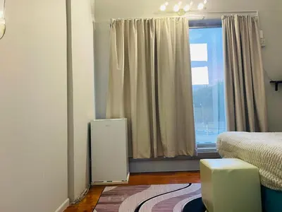 a bedroom with a bed and a large window at A guesthouse & Dormitory beds Claremont in Cape Town