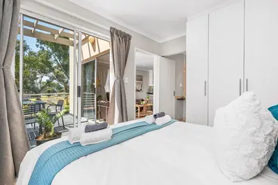 a bedroom with a large white bed and a balcony at Coral Grove in Cape Town