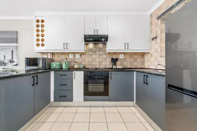 a kitchen with white cabinets and a stove top oven at Coral Grove in Cape Town