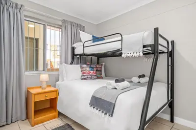 a bedroom with two bunk beds and a table at Coral Grove in Cape Town