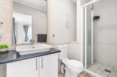 a white bathroom with a toilet and a sink at Coral Grove in Cape Town
