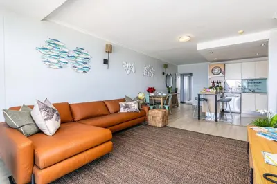 a living room with a brown couch and a kitchen at Blu Horizon in Cape Town