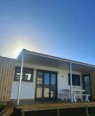 a tiny house with a picnic table on a deck at Logans place in Hermanus