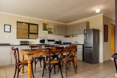 a kitchen with a table and chairs and a refrigerator at Bona Vista in Pringle Bay