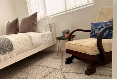 a bedroom with a bed and a chair and a window at Crescent House in Franschhoek