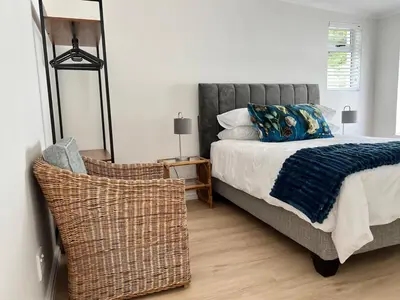 a bedroom with a bed and a wicker chair at Mountain View Voëlklip One Bedroom in Hermanus
