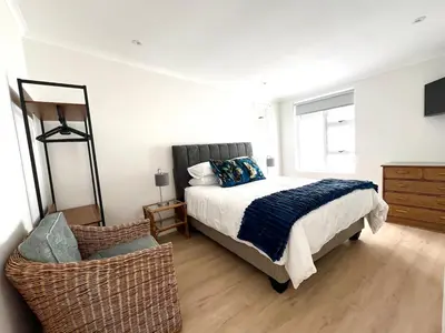 a bedroom with a bed and a chair at Mountain View Voëlklip One Bedroom in Hermanus