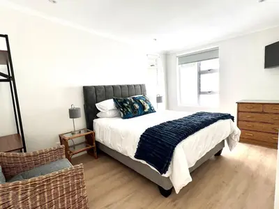 a bedroom with a large bed and a chair at Mountain View Voëlklip One Bedroom in Hermanus