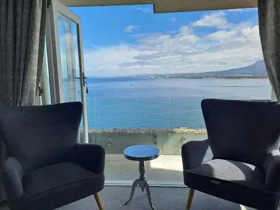 a room with two chairs and a view of the water at Boutique Inn - Azure in Gordonʼs Bay