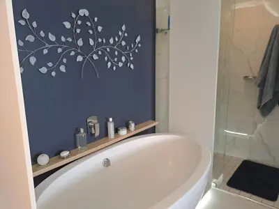 a bathroom with a tub and a shower and a toilet at Boutique Inn - Azure in Gordonʼs Bay