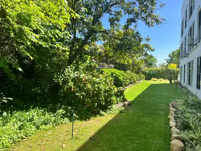 a garden with green grass and trees and a building at The Onyx Stellenbosch in Stellenbosch