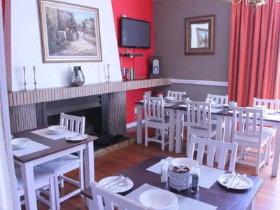 a dining room with a table and chairs and a fireplace at The Boston Guest House in Bellville