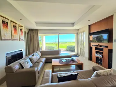 a living room with a couch and a table and a tv at Beachfront Golf Estate Escape in Strand in Strand