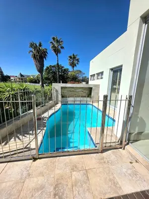 a swimming pool in front of a building at Beachfront Golf Estate Escape in Strand in Strand