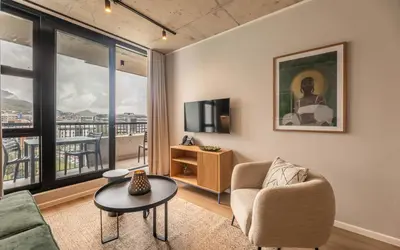a living room with a couch and a tv and a table at 622 Riverlands - Lux 2 Bedroom Apartment in Cape Town