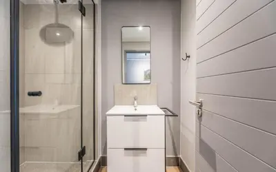 a white bathroom with a sink and a mirror at 622 Riverlands - Lux 2 Bedroom Apartment in Cape Town